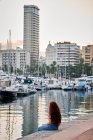 Giovane donna rossa seduta guarda un porto di una città — Foto stock