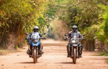 Two men riding their adventure motorbike on dirt road in Cambodia — Stock Photo