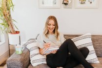 Beautiful young woman making notes at home — Stock Photo
