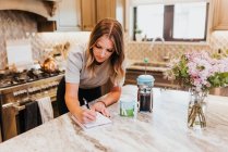 Молода жінка використовує цифровий планшет на кухні — стокове фото