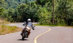 Homem montando sua moto de aventura na estrada ventosa no Camboja — Fotografia de Stock