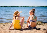 Duas adolescentes tween meninas em maiôs na margem do lago. — Fotografia de Stock