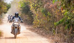 Група чоловіків їде на своєму пригодницькому мотоциклі по брудній дорозі в Камбоджі. — стокове фото