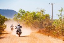 Hommes conduisant leurs motos d'aventure sur la route poussiéreuse au Cambodge — Photo de stock