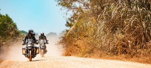 Homens montando suas motos de aventura na estrada empoeirada no Camboja — Fotografia de Stock