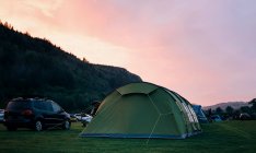 Tente au coucher du soleil avec un camping dans les montagnes. — Photo de stock