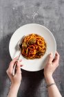 Espaguete caseiro com molho de tomate, parmesão e almôndegas em um fundo escuro e mãos femininas — Fotografia de Stock
