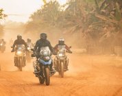 Grupo de hombres montando su moto de aventura en el camino de tierra en Camboya - foto de stock