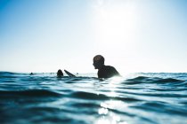 Surfer waiting for wave, sitting on board, blue — Stock Photo