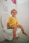 Porträt eines glücklichen Mädchens, das zu Hause auf der Toilette sitzt — Stockfoto
