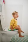 Portrait de fille heureuse assise sur les toilettes à la maison — Photo de stock
