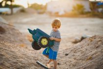 Young boy playing with toy trucks in the desert — Stock Photo