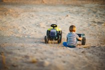 Молодий хлопчик грає з іграшковими вантажівками в пустелі — стокове фото