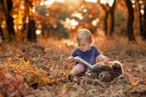 Маленький піщаник читає казкову книгу в осінньому лісі — стокове фото