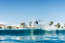 Человек серфинг и делать серфинг маневр на волне в море — стоковое фото