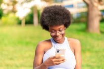 Afro femme de cheveux en utilisant son smartphone — Photo de stock