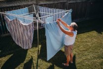 Senior mulher pendurado lavanderia em um varal ao ar livre. — Fotografia de Stock