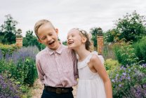 Boy and girl laughing happily in a beautiful flower field — Stock Photo