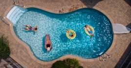 Вид сверху на семью, плавающую в бассейне в летний день. — стоковое фото