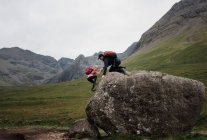 Папа помогал дочери взбираться на гору во время похода по Шотландскому нагорью — стоковое фото