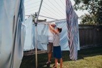 Older woman and boy hanging laundry on an outdoor clothesline. — Stock Photo