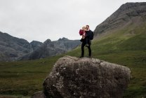 Padre abrazando a su hija después de escalar una roca gigante en Escocia - foto de stock