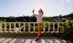 Femme faire un selfie dans un point de vue raconte le coucher du soleil — Photo de stock