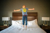 Маленький хлопчик стрибає на ліжку в спальні — стокове фото