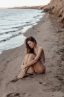 Schöne luxuriöse schlanke Mädchen in einem leichten Badeanzug am Strand am Meer. Sexy gebräunter Körper, flacher Bauch, perfekte Figur. Ruhe auf einer tropischen Insel. — Stockfoto