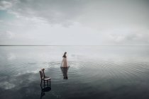 Una donna elegante è entrata in acqua. Tramonto e silhouette. Il concetto di unità con la natura. Silenzio! — Foto stock