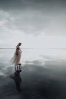 Una donna elegante è entrata in acqua. Tramonto e silhouette. Il concetto di unità con la natura. Silenzio! — Foto stock