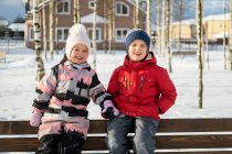 Dos niños se divierten caminando en el pueblo de invierno. - foto de stock