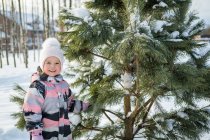 The cute girl standing by the tree and looking at the camera. — Stock Photo
