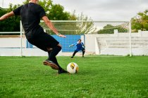 Jugador de fútbol dispara un penal contra un portero en un campo de fútbol - foto de stock