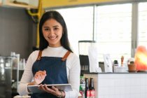Веселая зрелая официантка ждет клиентов в кафе. Успешный владелец малого бизнеса. — стоковое фото