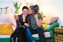Queer Couple laying in couch with their pet dog. — Stock Photo