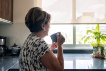 Junge Frau trinkt Kaffee in der Küche — Stockfoto