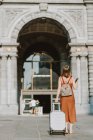 Jeune femme avec valise marchant dans la ville — Photo de stock