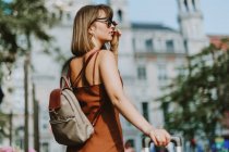 Schöne junge Frau mit langen Haaren in Sonnenbrille und Jacke posiert auf der Straße — Stockfoto