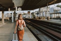 Giovane donna con valigia alla stazione ferroviaria — Foto stock