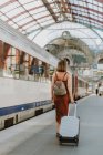 Giovane donna con valigia alla stazione ferroviaria — Foto stock