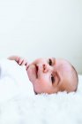 Portrait of a cute baby boy lying on a white bed — Stock Photo