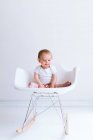 Petit garçon assis sur une chaise en studio — Photo de stock