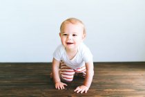 Cute little baby boy sitting on the floor, looking at camera, smiling, lying on the carpet, — Stock Photo
