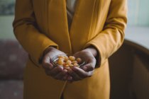 Lamponi gialli in un piatto di vetro nelle mani di una ragazza in una giacca gialla — Foto stock