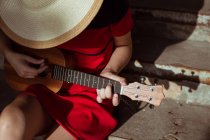 Vista dall'alto di una ragazza seduta che suona l'ukulele, primo piano — Foto stock