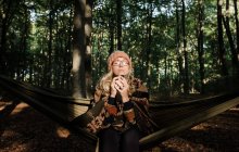 Porträt einer schönen jungen Frau in einem schwarzen Kleid mit Rucksack und Schal im Wald — Stockfoto