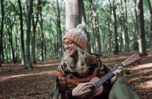Junge Frau mit Gitarre im Wald — Stockfoto