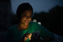 Jeune femme regardant mobile sur le toit en heure bleue — Photo de stock
