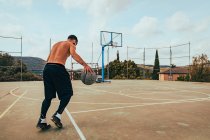 Rapaz treinando sozinho em uma quadra de basquete — Fotografia de Stock